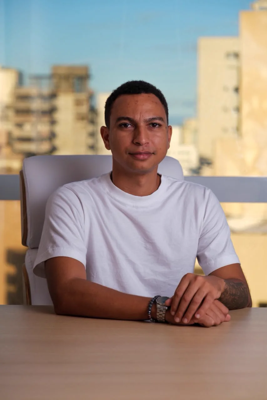 Yury Sixel de camiseta branca, sentado à mesa do consultório